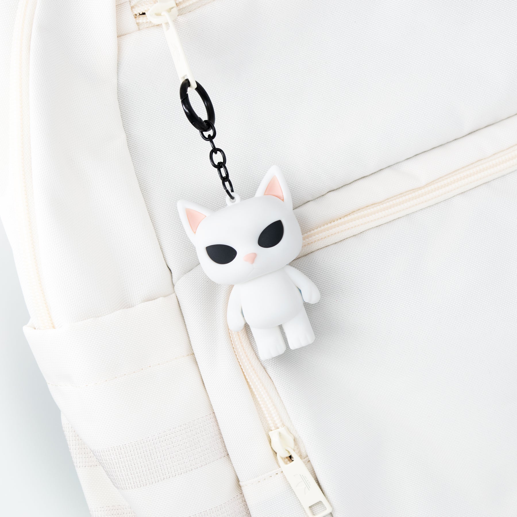 White cat-shaped bag charm keychain James meme cat with a black chain on a white background